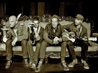 Coldplay  Sepia version of the band shot on a couch.